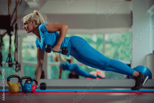 Beautiful young woman working out with dumbbells in gym