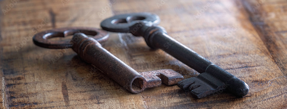 Two antique door keys on wooden background. Selective focus. Two antique door keys on wooden background. Selective focus.
