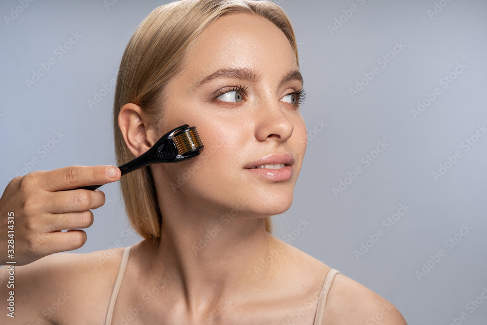 Beautiful relaxed girl using a face massager Beautiful relaxed girl using a face massager