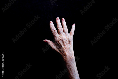 Open white old lady hand with palm facing down on a black background