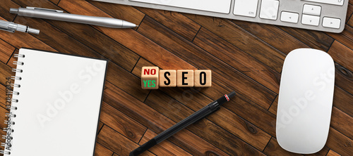 cubes with message SEO and the option between YES and NO in front of a keayboard on wooden background photo