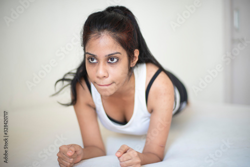 Indian brunette girl performing yoga sports  exercise in sportswear in front of a white background. Indian lifestyle