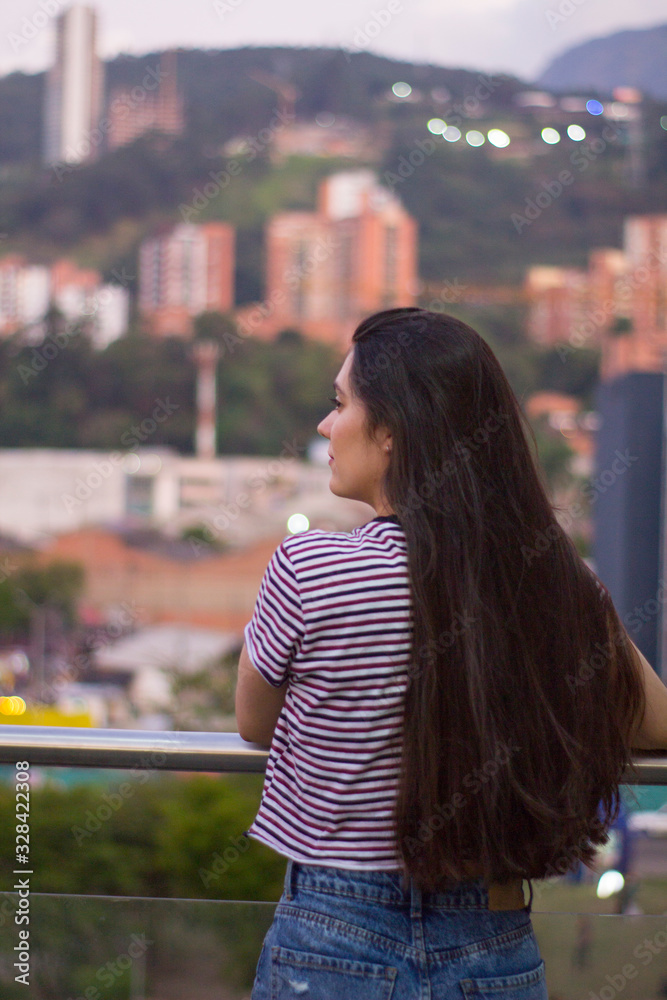 Chica de perfil mirando a la ciudad. Montañas y edificios al fondo