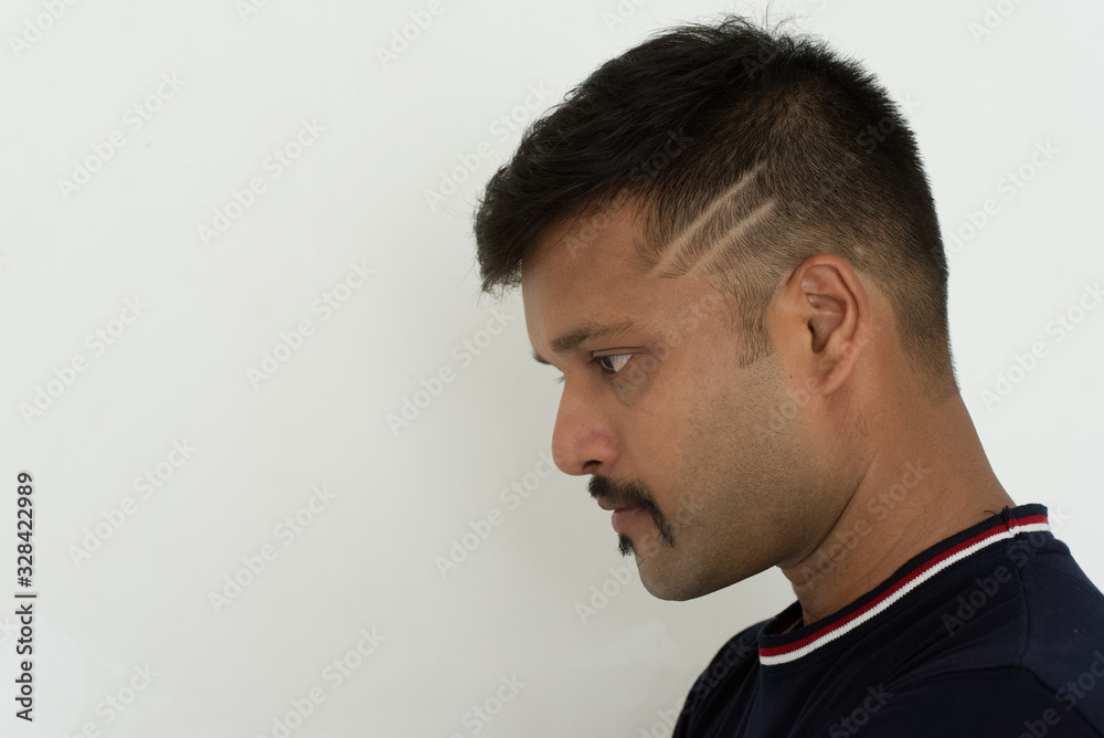 Obraz premium Portrait of a handsome and intelligent Indian brunette man wearing a solid black t shirt standing before a copy space white background. Indian lifestyle and fashion portrait
