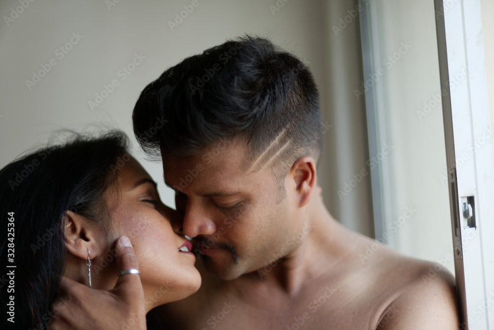 Indian Bengali beautiful brunette couple sharing intimate romantic moments standing in front of a window in white background. Indian lifestyle and romantic couple Indian Bengali beautiful brunette couple sharing intimate romantic moments standing in front of a window in white background. Indian lifestyle and romantic couple