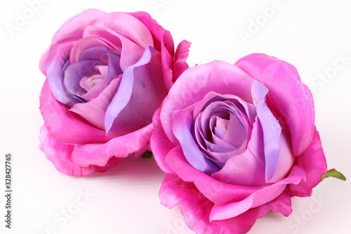 Artificial violet roses on white background