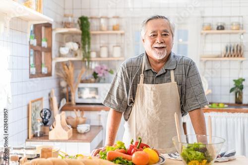 Fotografie Senior Asian elder man happy living in home kitchen