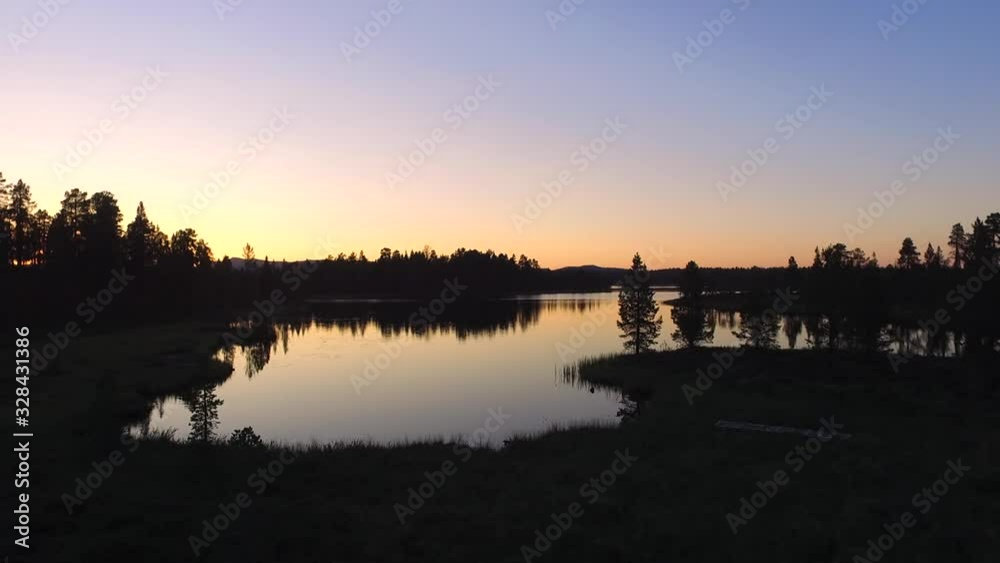 Beautiful sunset over a reflective lake in the north of Sweden. High contrast drone footage with beautiful pines, water and sky Beautiful sunset over a reflective lake in the north of Sweden. High contrast drone footage with beautiful pines, water and sky