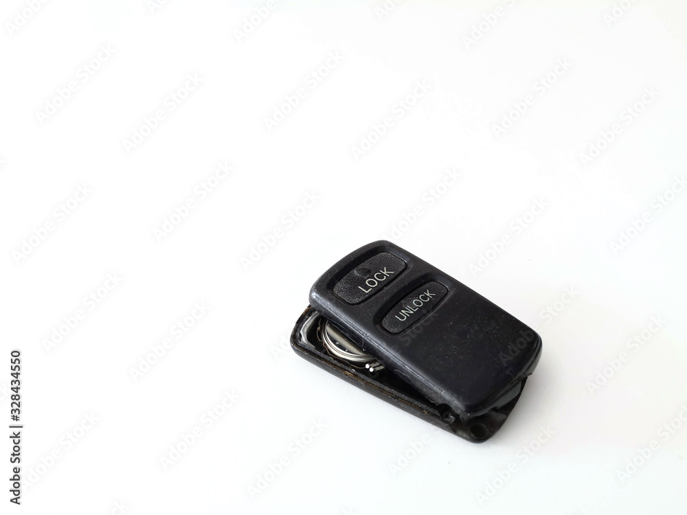 The black remote control has two buttons with lock and unlock for car, gate, garrage is broken, seeing battery, doesn't work, tha cap is opened on white background The black remote control has two buttons with lock and unlock for car, gate, garrage is broken, seeing battery, doesn't work, tha cap is opened on white background