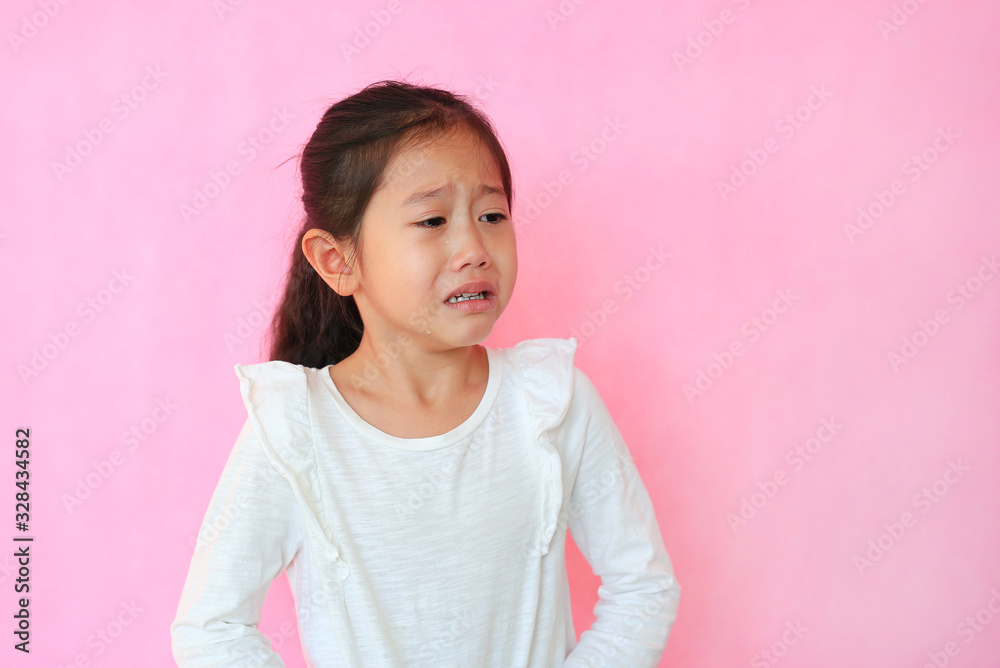Portrait closeup asian little child girl crying isolated on pink background with copy space. Kid with sad expressions. Portrait closeup asian little child girl crying isolated on pink background with copy space. Kid with sad expressions.