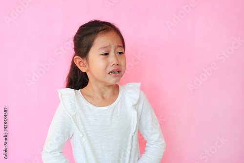 Leinwand Poster Portrait closeup asian little child girl crying isolated on pink background with copy space