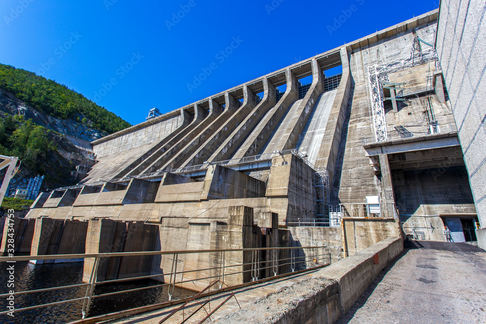 Industrial photography. The main building with turbines of the Zeya hydroelectric station on the background of a concrete dam.