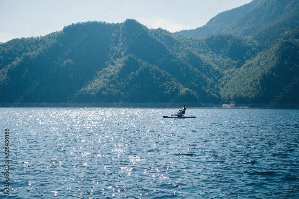 the concept of boating, recreation, travel-a man rides a catamaran. Boating on the lake