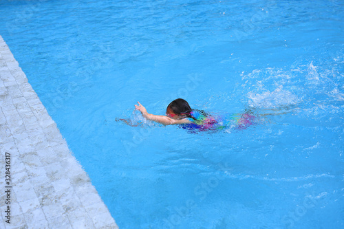 Asian little child girl learning to swim in pool. Schoolgirl practicing to swimming.