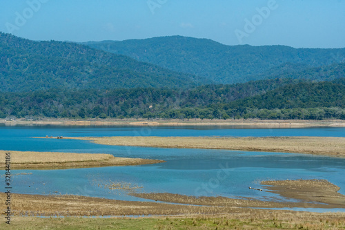 wild asian elephant family or herd with baby elephants or calf at scenic view and landscape of ramganga river in dhikala zone of jim corbett national park, uttarakhand, india