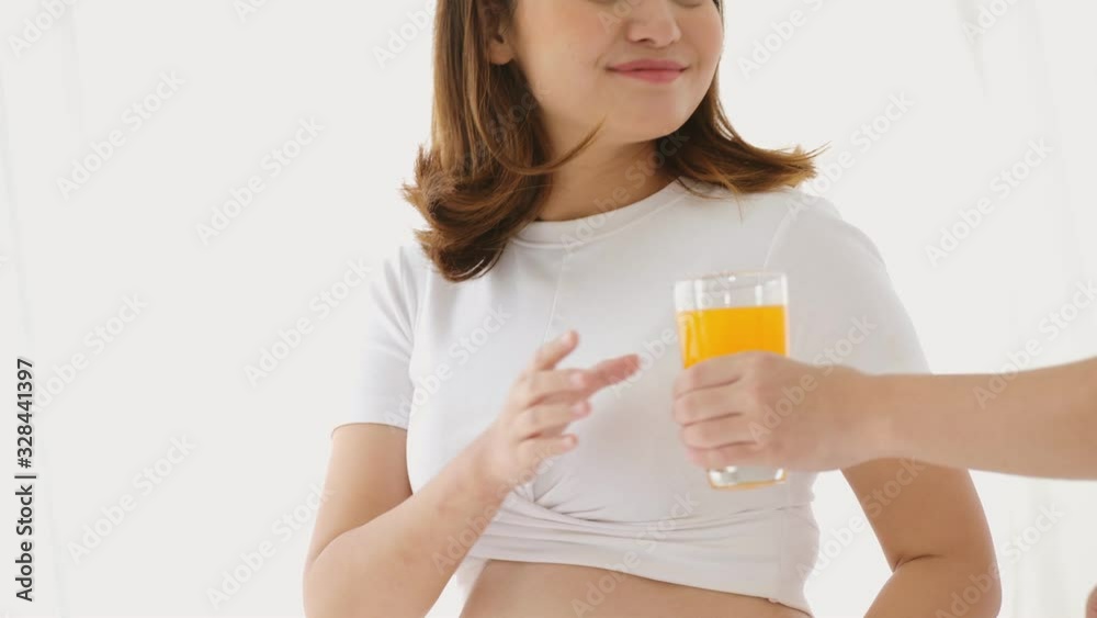 Tilting scene video of a pregnant woman taking a glass of orange juice from her husband. She drinking it. That's made her so freshener. Tilting scene video of a pregnant woman taking a glass of orange juice from her husband. She drinking it. That's made her so freshener.