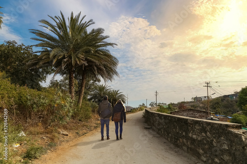 Couple take a stroll along a mountain road at Mount Abu Rajasthan at sunrise. Mount Abu is a hill station in western India’s Rajasthan state