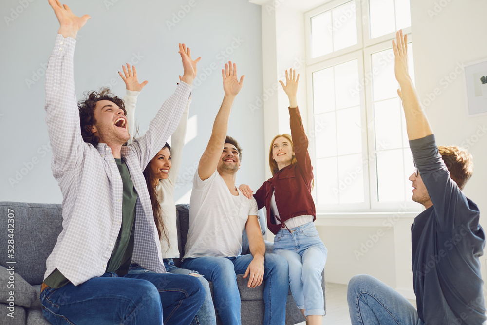 Happy people cheerfully connected their hands in a room with a window.