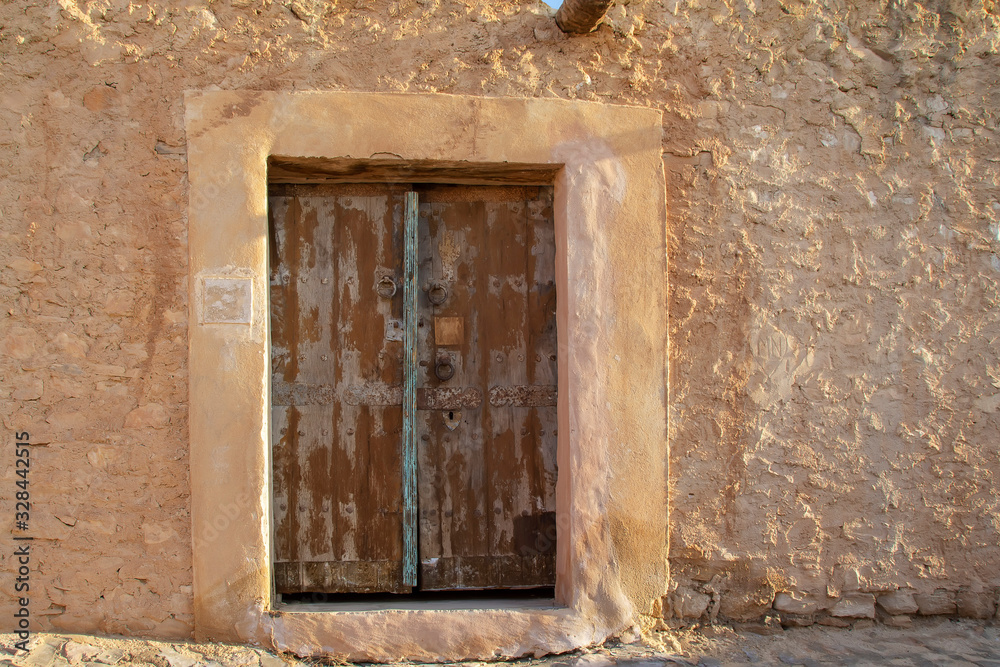 North African-style wooden door to the wall of a ruined stone North African-style wooden door to the wall of a ruined stone