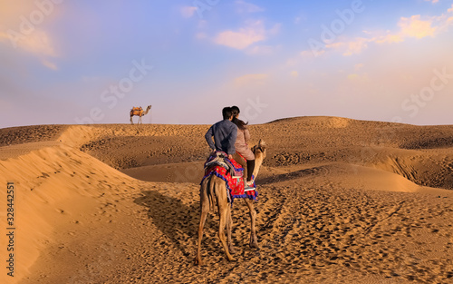 Thar desert at Jaisalmer Rajasthan with view of tourist couple enjoying a camel safari at sunset