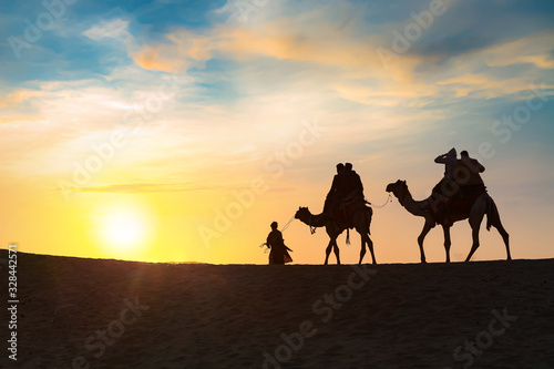 Tourist enjoy camel safari at sunset on the dunes of Thar desert at Jaisalmer Rajasthan India