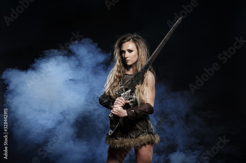 Beautiful female viking woman warrior in battle with big two-handed sword. Ancient times. Amazon fantasy blonde hair sexy girl.
