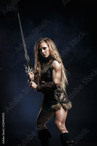 Beautiful female viking woman warrior in battle with big two-handed sword. Ancient times. Amazon fantasy blonde hair sexy girl.