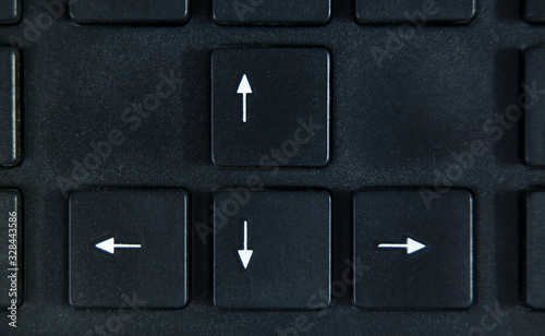 4 white arrows on the black buttons of black keyboard close up