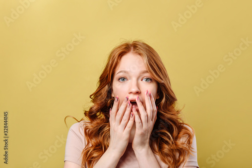 Astonished young woman put her palms to her mouth