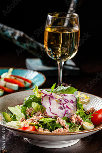 Spanish cuisine. Fish salad of mix salad  cherry tomatoes  quail eggs  capers  avacado  arugula  tuna. Serving dishes in a restaurant in a white plate. background image  copy space