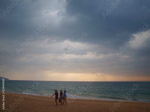 A plane in the sky and a thundercloud over the sea. The plane flies in a thunderstorm. People leave a deserted beach before a thunderstorm. Rushing people running on the sand.