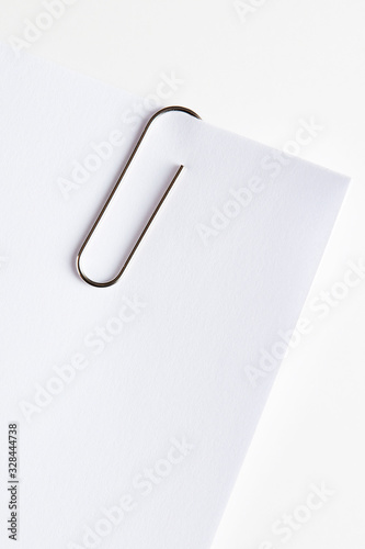 Metal paper clip attached to the corner of a blank white paper