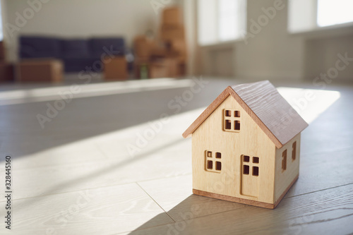 Model of the wooden house on the floor in the new bright sunny house.