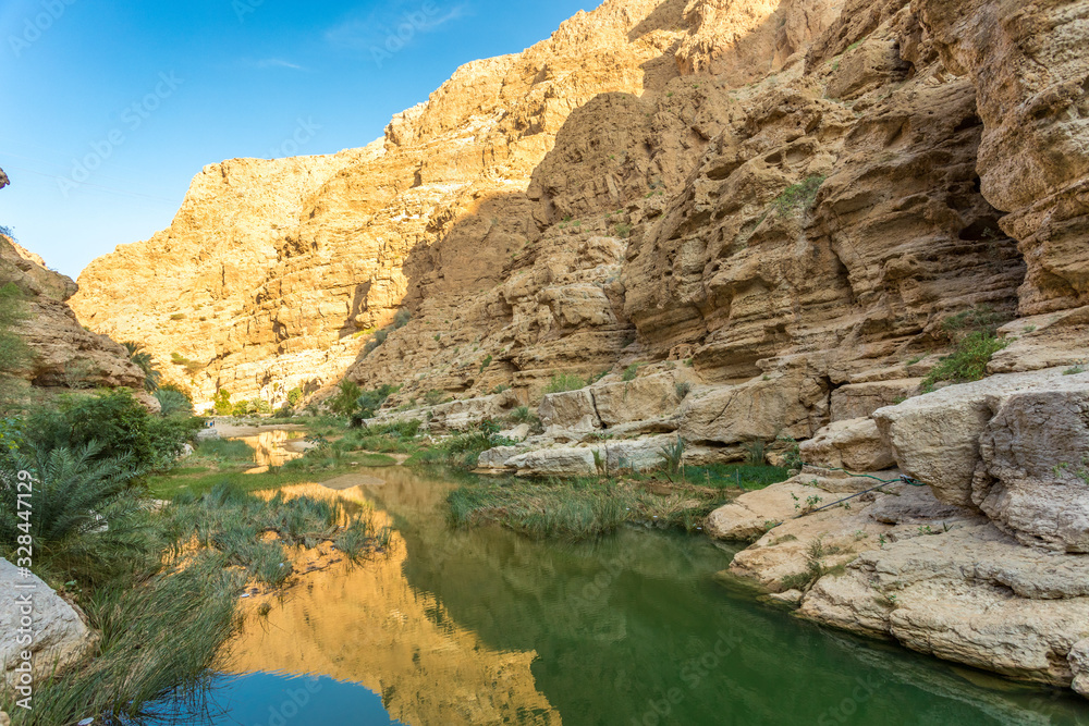 Wadi Shab river canyon with rocky cliffs and green water springs - Sultanate of Oman