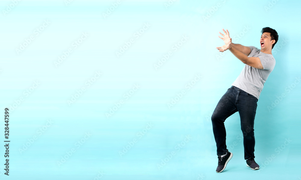 full body Portrait of handsome,Shock and surprise face of asian man Pointing finger on empty space isolated on blue background in studio With copy space.