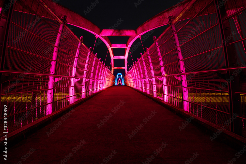 Bright red LEDs illuminate pedestrian walkway over highway at night