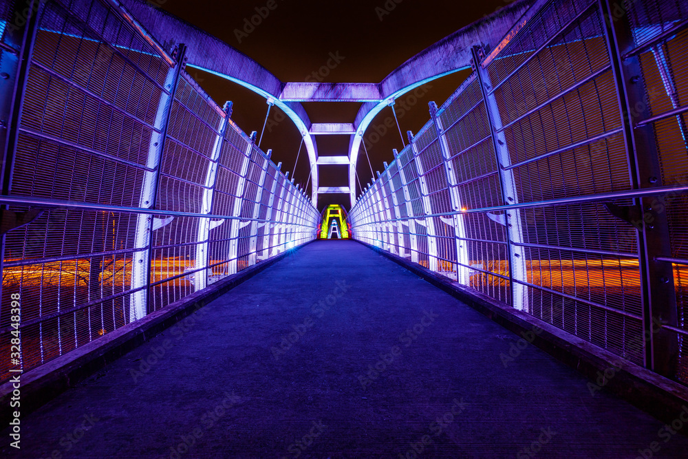 Bright white LEDs illuminate pedestrian walkway over highway at night