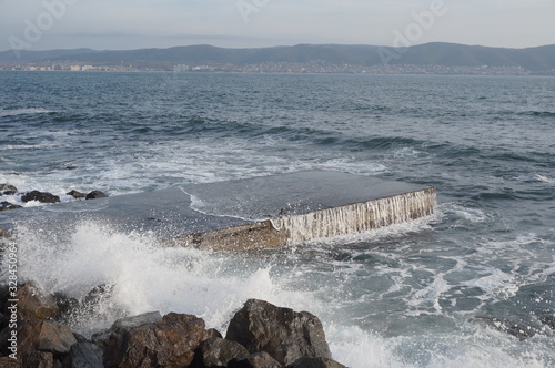 Sea water on a stone slab, an incident wave is breaking on stones, water splashes.