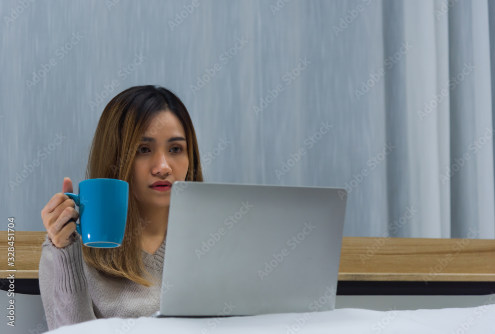 Young Asian beautiful woman using computer notebook to social online and drink a glass of milk on bed with vacant eyes in bedroom at night time. Insomnia effect Young Asian beautiful woman using computer notebook to social online and drink a glass of milk on bed with vacant eyes in bedroom at night time. Insomnia effect