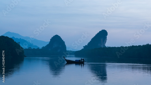 A fisherman driving a boat on river and Khao kha nab nam on background, landmark in Krabi  province, Thailand