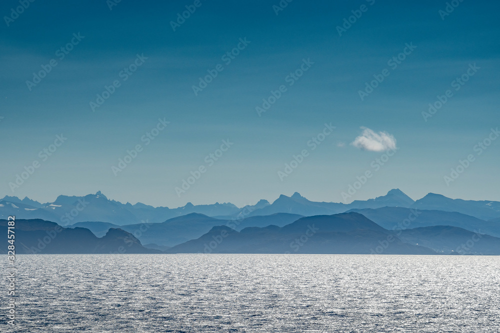 Land in Sicht - Verblauung der Küste in Norwegen mit Meer, Bergen, blauem Himmel und einzelner Wolke von der Seeseite aus gesehen