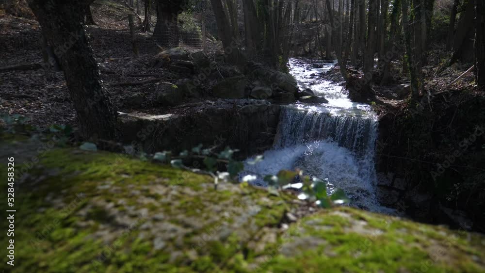 Natural spring water flows down a waterfall in the forest on a sunny day Natural spring water flows down a waterfall in the forest on a sunny day