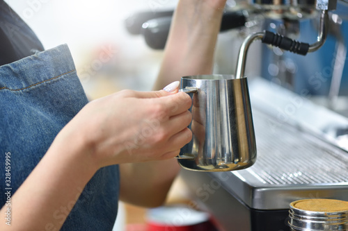 Bartender prepare coffee on a coffee machine and whips milk with steam, hands closeup. Small business concept