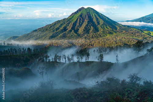 volcano Ruang next to Ijen covered in sulphur coming out uf Ijen. a mystic view early in the morning in Java, Indonesia photo