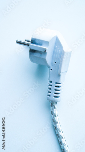 White electric cable from the iron on a light background. Plug for socket. Conductor of electricity. Household chores. Energy saving.