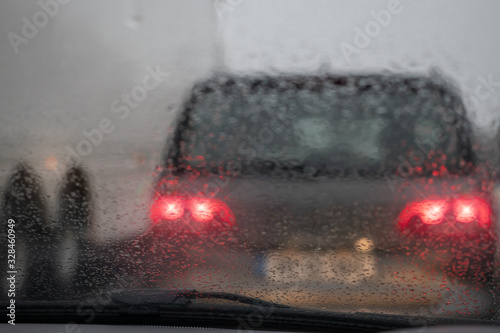 View from a car on a traffic jam on a rainy gloomy day, Raindrops on the glass in focus, commuters cars out of focus. Concept heavy urban traffic.