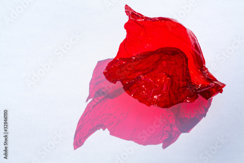 Billede på lærred Thin sheet of red colour cellophane with shiny crumpled surface texture  on whit