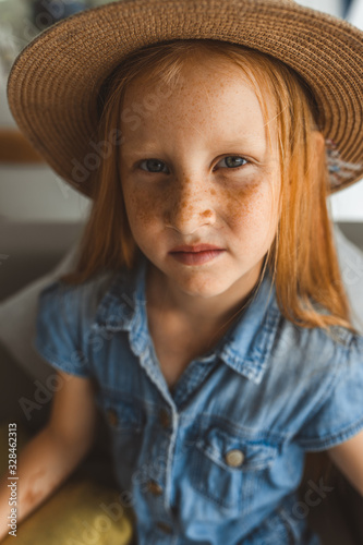 Little girl with red hair shows different emotions. Sadness, joy and happiness. She smiles and cries. In jeans with skin pigment on his face, freckles overlooking the sea. FASHIONABLE CHILD