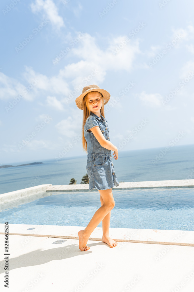 Little girl with red hair shows different emotions. Sadness, joy and happiness. She smiles and cries. In jeans with skin pigment on his face, freckles overlooking the sea. FASHIONABLE CHILD Little girl with red hair shows different emotions. Sadness, joy and happiness. She smiles and cries. In jeans with skin pigment on his face, freckles overlooking the sea. FASHIONABLE CHILD