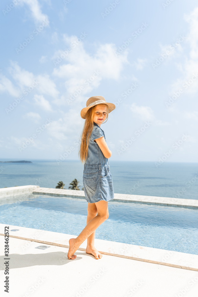 Little girl with red hair shows different emotions. Sadness, joy and happiness. She smiles and cries. In jeans with skin pigment on his face, freckles overlooking the sea. FASHIONABLE CHILD Little girl with red hair shows different emotions. Sadness, joy and happiness. She smiles and cries. In jeans with skin pigment on his face, freckles overlooking the sea. FASHIONABLE CHILD
